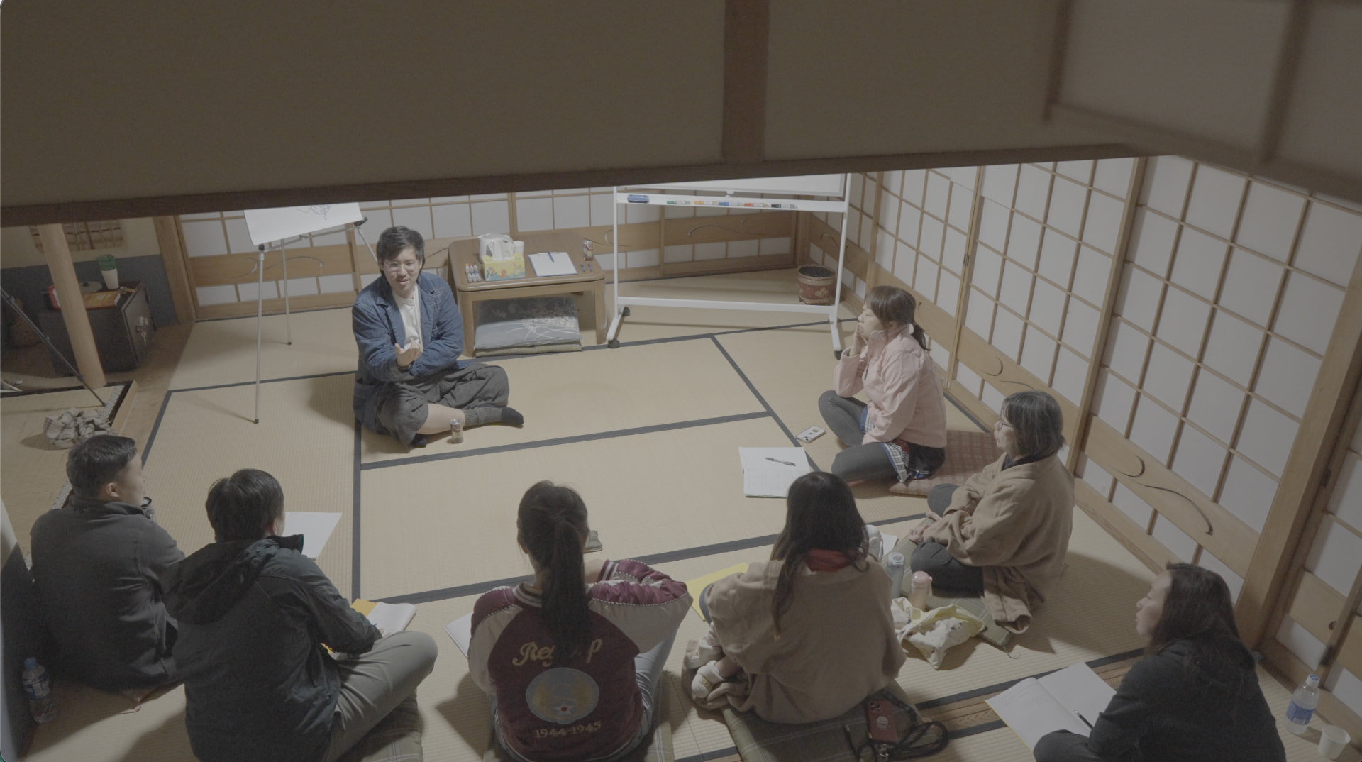 A small group seated in a circle on tatami mats during a workshop